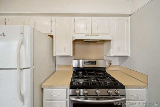 kitchen featuring white fridge, gas range, and white cabinetry