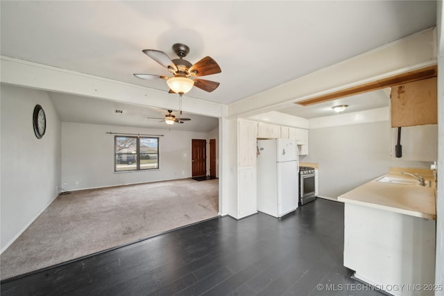 kitchen with dark wood-type flooring, ceiling fan, white fridge, sink, and stainless steel range