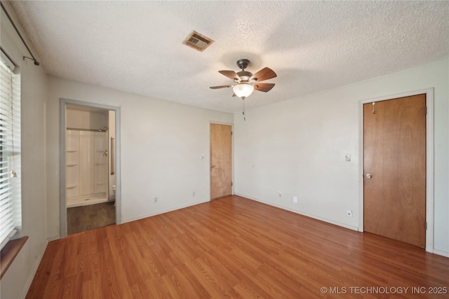 unfurnished bedroom with ensuite bathroom, a textured ceiling, and hardwood / wood-style floors