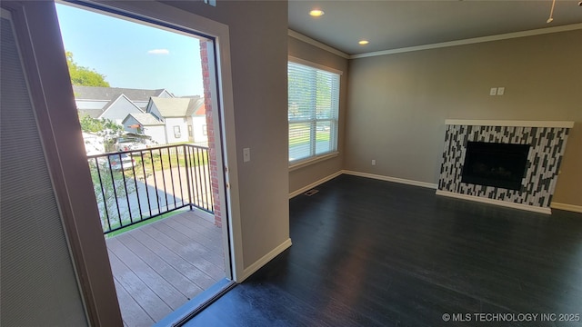 doorway to outside featuring crown molding, a stone fireplace, and dark hardwood / wood-style floors