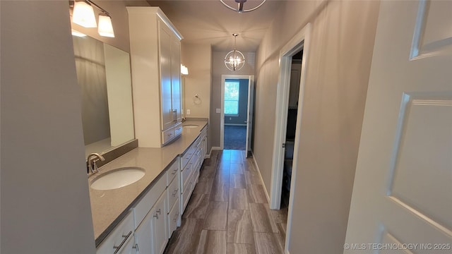 bathroom with vanity, wood-type flooring, and an inviting chandelier