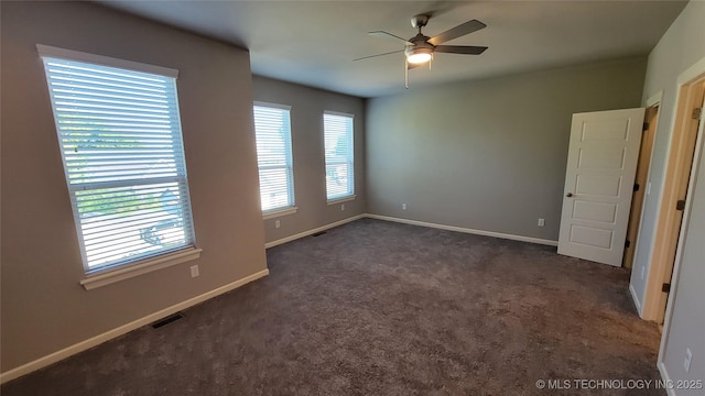 spare room with ceiling fan and dark carpet