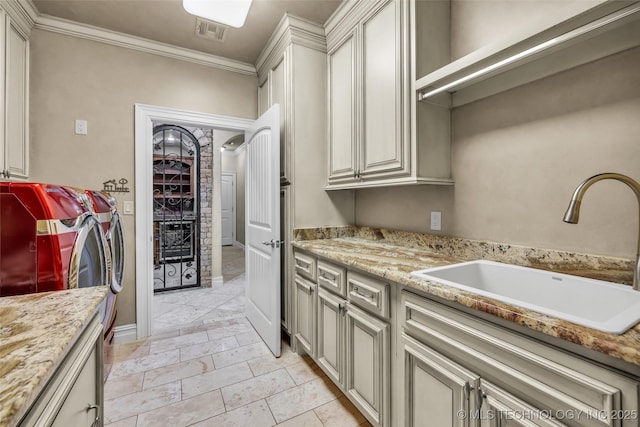 kitchen featuring light stone counters, ornamental molding, washer and clothes dryer, and sink