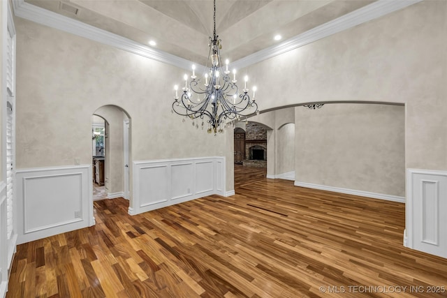 unfurnished dining area featuring ornamental molding, wood-type flooring, and a high ceiling