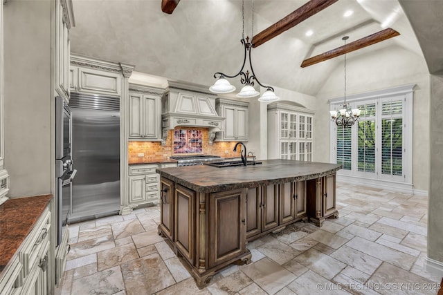 kitchen with premium range hood, appliances with stainless steel finishes, high vaulted ceiling, cream cabinets, and an island with sink