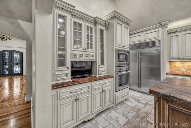 kitchen with built in appliances, dark stone counters, and french doors