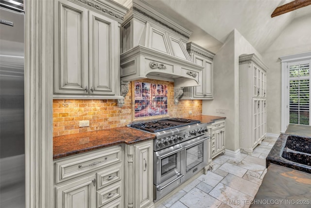 kitchen with lofted ceiling, custom exhaust hood, dark stone countertops, high quality appliances, and decorative backsplash