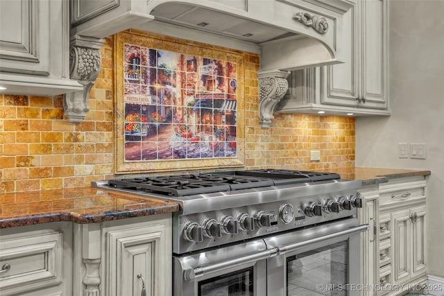 kitchen with double oven range, backsplash, dark stone counters, and custom range hood