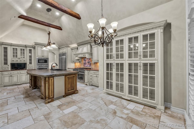 kitchen featuring sink, built in appliances, custom range hood, an island with sink, and decorative light fixtures