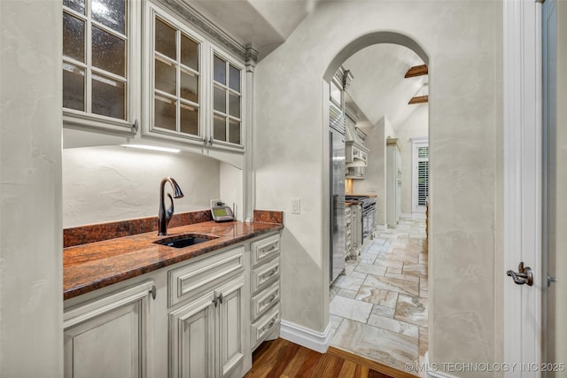 interior space featuring vaulted ceiling, appliances with stainless steel finishes, sink, and dark stone countertops