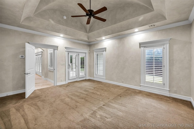 carpeted spare room featuring a raised ceiling, ornamental molding, ceiling fan, and french doors