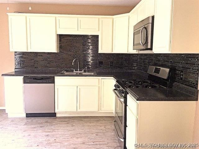 kitchen with appliances with stainless steel finishes, sink, white cabinets, and decorative backsplash