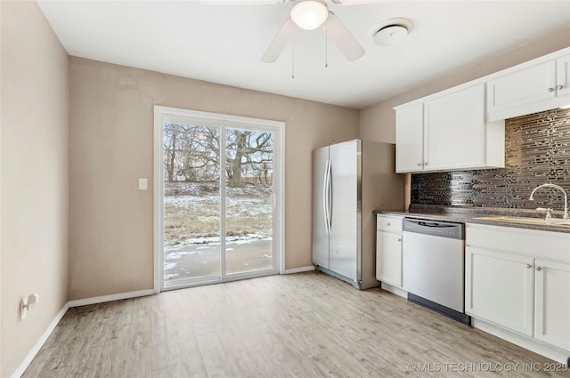 kitchen featuring sink, appliances with stainless steel finishes, white cabinets, light hardwood / wood-style floors, and backsplash