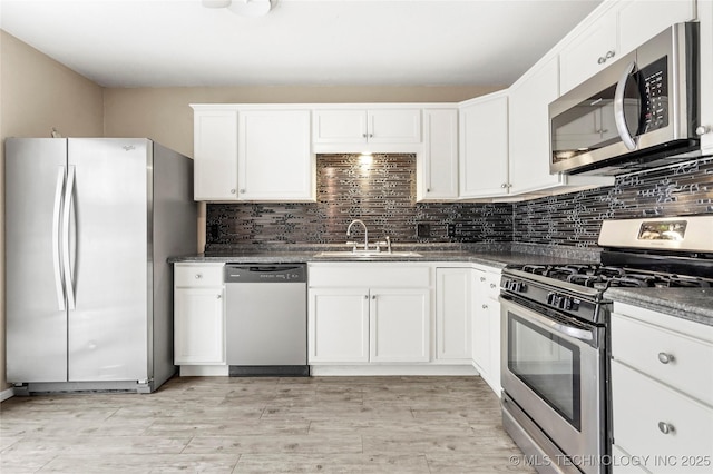 kitchen with sink, backsplash, stainless steel appliances, light hardwood / wood-style floors, and white cabinets