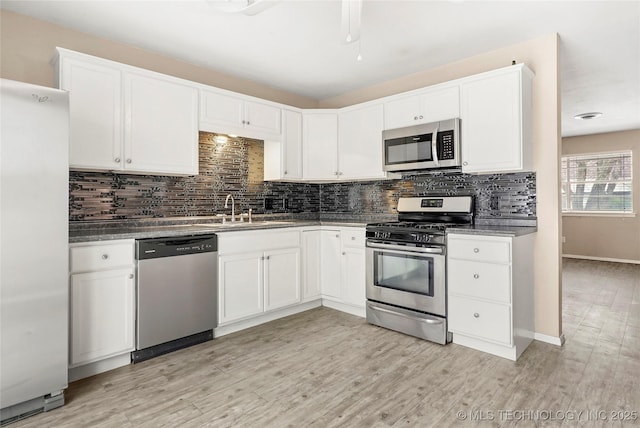 kitchen featuring tasteful backsplash, white cabinetry, sink, light hardwood / wood-style floors, and stainless steel appliances