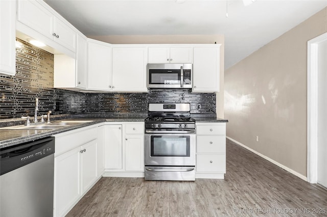 kitchen with white cabinetry, sink, decorative backsplash, hardwood / wood-style flooring, and stainless steel appliances