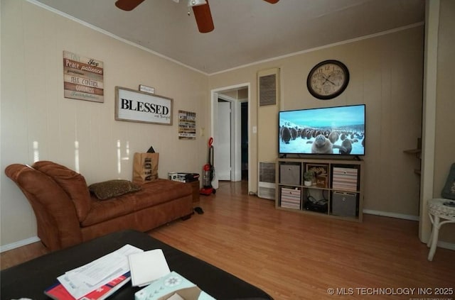 living room with wood-type flooring, ornamental molding, and ceiling fan