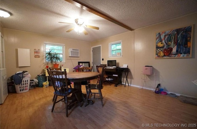 dining space with ceiling fan, hardwood / wood-style floors, a wall unit AC, and a textured ceiling