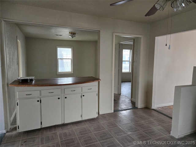 kitchen with a healthy amount of sunlight, white cabinets, and ceiling fan