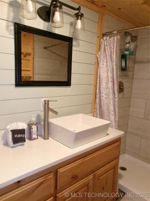 bathroom with vanity, a shower with curtain, and wood walls