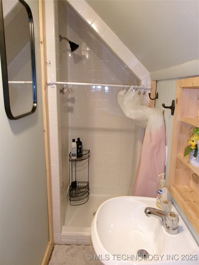 bathroom featuring vaulted ceiling and a tile shower