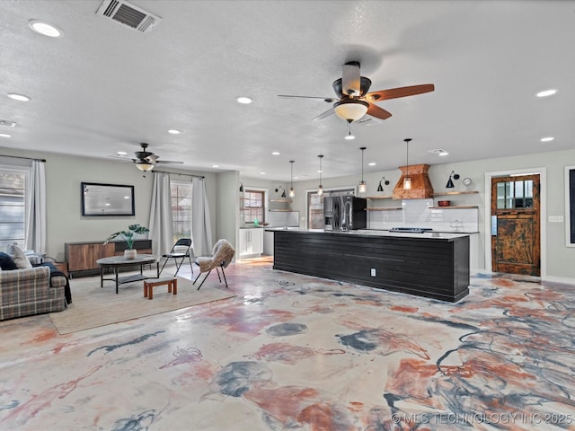 kitchen with pendant lighting, custom exhaust hood, fridge with ice dispenser, and a center island with sink