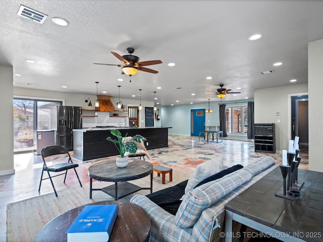 living room with ceiling fan, a textured ceiling, and light wood-type flooring