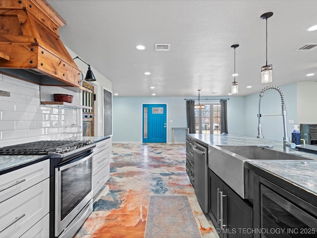 kitchen with sink, appliances with stainless steel finishes, white cabinetry, backsplash, and decorative light fixtures