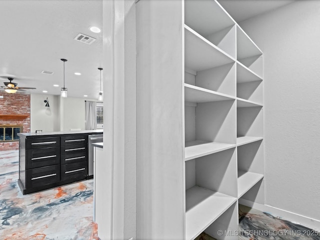 walk in closet featuring a brick fireplace and ceiling fan