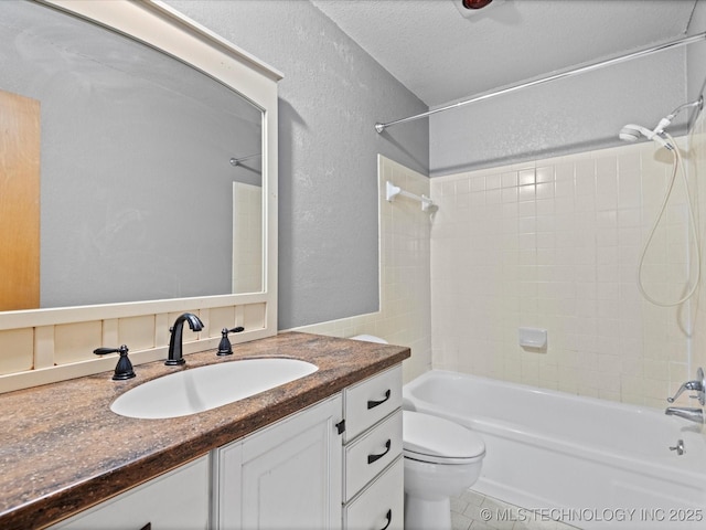 full bathroom with tiled shower / bath combo, vanity, a textured ceiling, tile patterned floors, and toilet