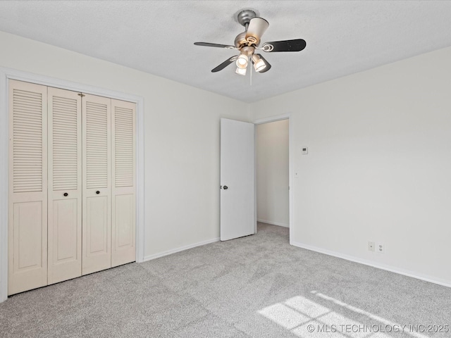 unfurnished bedroom featuring ceiling fan, light colored carpet, a closet, and a textured ceiling