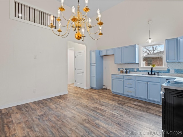 kitchen with sink, tasteful backsplash, decorative light fixtures, hardwood / wood-style flooring, and a towering ceiling