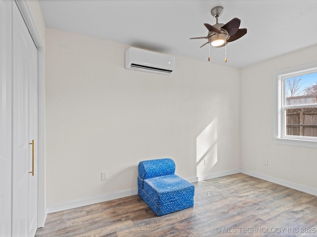 sitting room featuring hardwood / wood-style flooring, a wall mounted AC, and ceiling fan