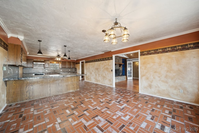 kitchen with hanging light fixtures, tasteful backsplash, ornamental molding, ceiling fan with notable chandelier, and kitchen peninsula