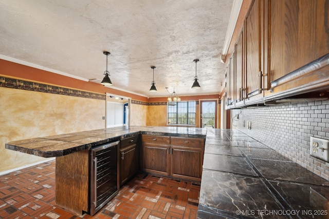 kitchen with hanging light fixtures, a kitchen breakfast bar, kitchen peninsula, beverage cooler, and backsplash