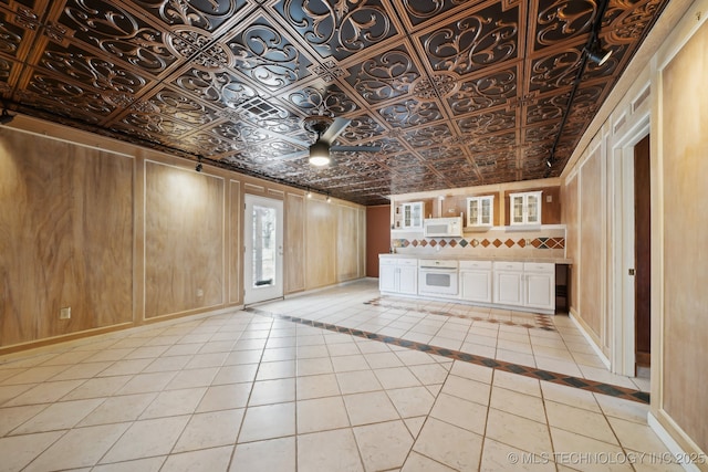 unfurnished living room with light tile patterned flooring and wood walls