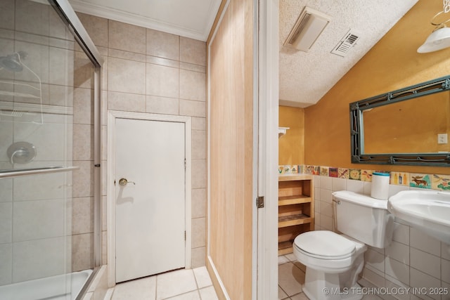 bathroom featuring a shower with door, tile walls, tile patterned flooring, a textured ceiling, and toilet