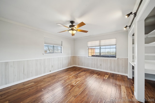 unfurnished room with ceiling fan, plenty of natural light, ornamental molding, and dark hardwood / wood-style flooring