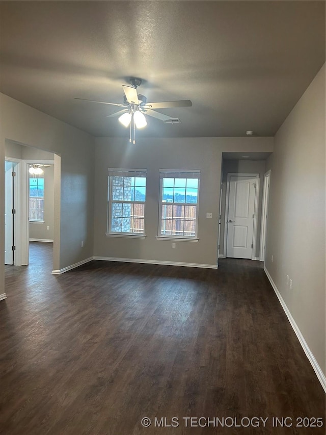 empty room with dark wood-type flooring, ceiling fan, and plenty of natural light