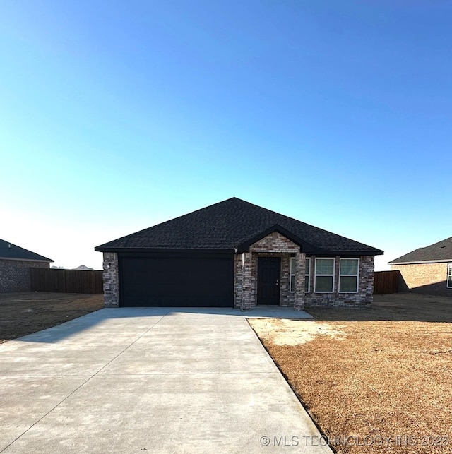 view of front facade featuring driveway, an attached garage, and fence