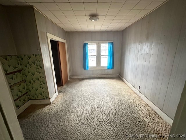 carpeted spare room with wood walls