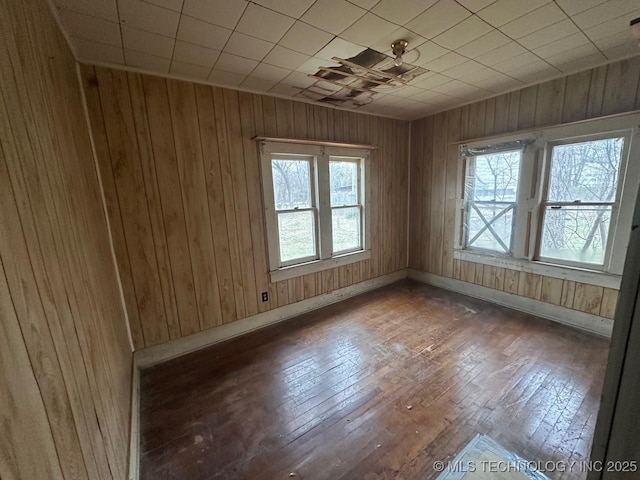 spare room with dark hardwood / wood-style floors and wood walls