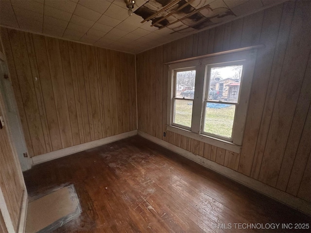 unfurnished room featuring dark wood-type flooring and wooden walls