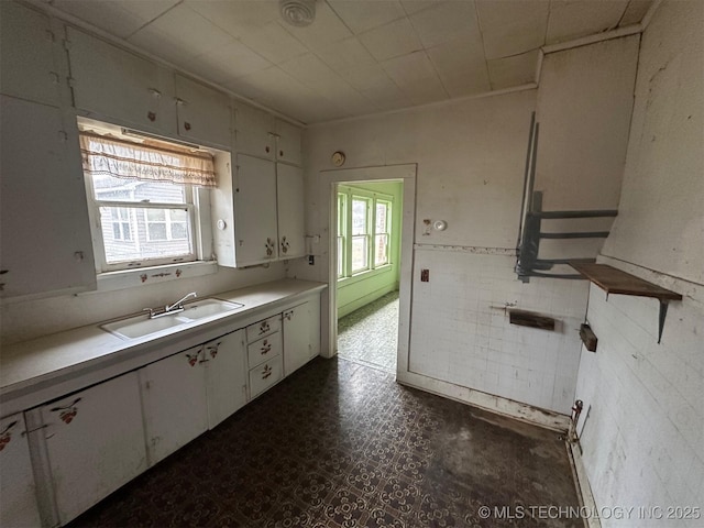 kitchen with tile walls, sink, and white cabinets