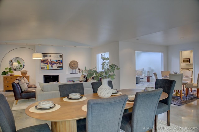 2411 E 72nd Pl Unit 2-A-3, Tulsa, OK 74136 - dining space featuring concrete flooring, a fireplace, and lofted ceiling