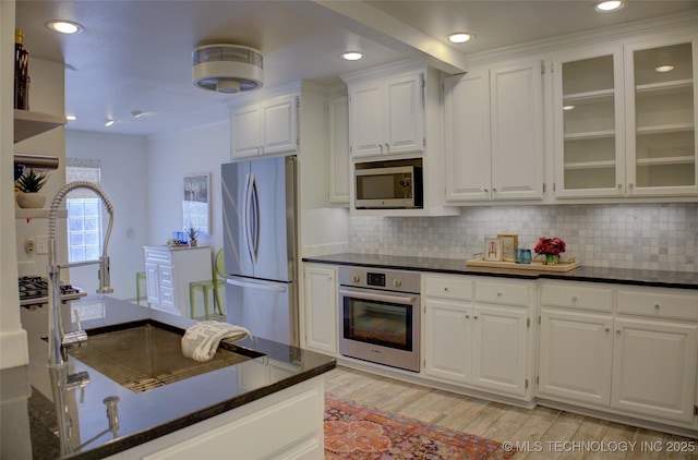 2411 E 72nd Pl Unit 2-A-3, Tulsa, OK 74136 - kitchen with stainless steel appliances, white cabinets, light wood-type flooring, decorative backsplash, and recessed lighting