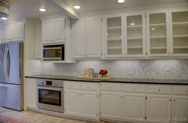 2411 E 72nd Pl Unit 2-A-3, Tulsa, OK 74136 - kitchen with appliances with stainless steel finishes, white cabinetry, dark countertops, glass insert cabinets, and tasteful backsplash