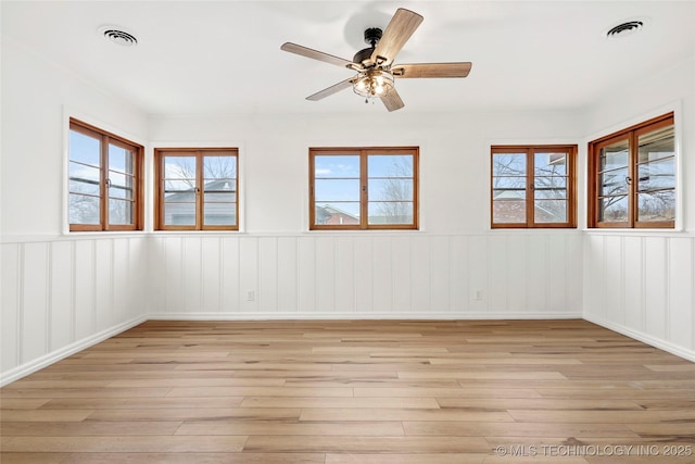 spare room with ceiling fan, a wealth of natural light, and light wood-type flooring