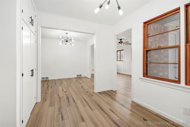 empty room featuring crown molding, ceiling fan with notable chandelier, and light wood-type flooring