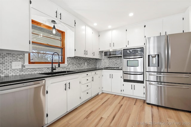 kitchen featuring sink, appliances with stainless steel finishes, white cabinetry, decorative backsplash, and light wood-type flooring